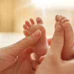 Mum making baby massage, mother massaging infant bare foot, prev